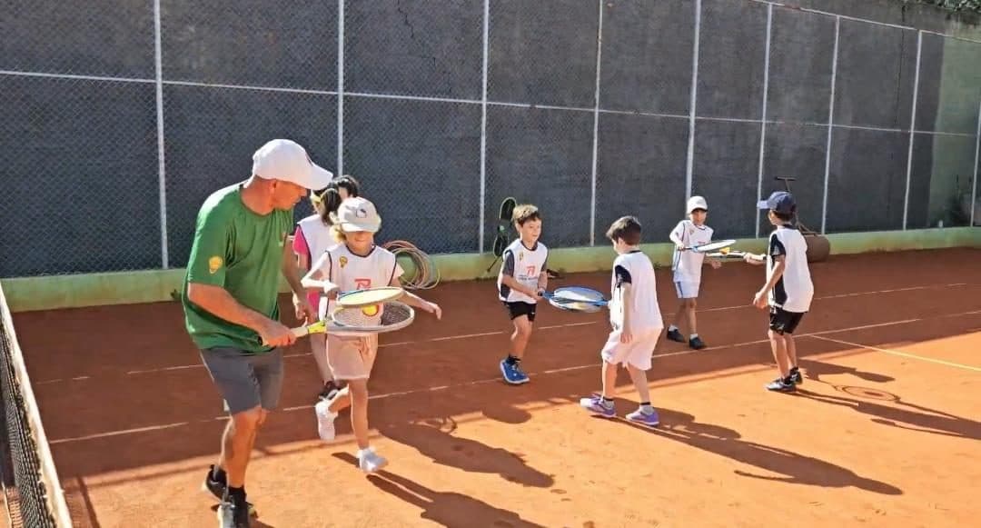 Professor conduz o aquecimento com a turma na quadra