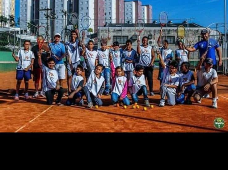 Alunos comemorando em quadra de saibro na sede do projeto